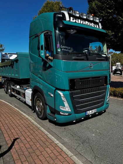 Türkiser Volvo-Kipper-LKW mit Aufschrift "Bahmen" auf der Frontscheibe, geparkt am Straßenrand bei sonnigem Wetter.